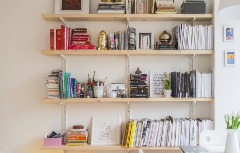 Wooden wall shelves neatly stacked with books, magazines and small boxes