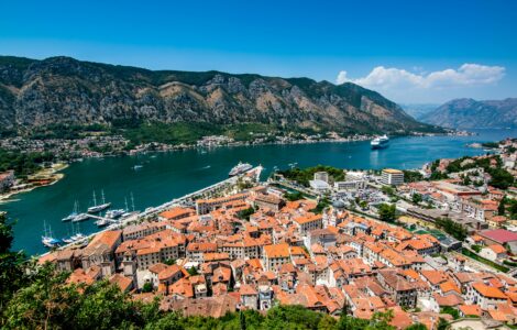 Red-roofed old town on a bay surrounded by mountains, seen from above