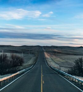 Straight two-lane road running through open prairie under a wide sky
