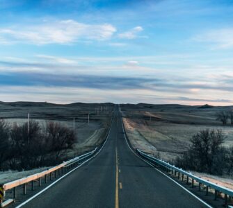 Straight two-lane road running through open prairie under a wide sky