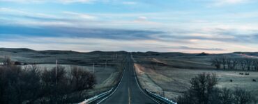 Straight two-lane road running through open prairie under a wide sky