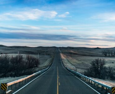 Straight two-lane road running through open prairie under a wide sky