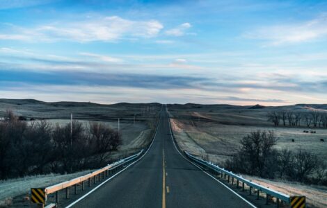 Straight two-lane road running through open prairie under a wide sky