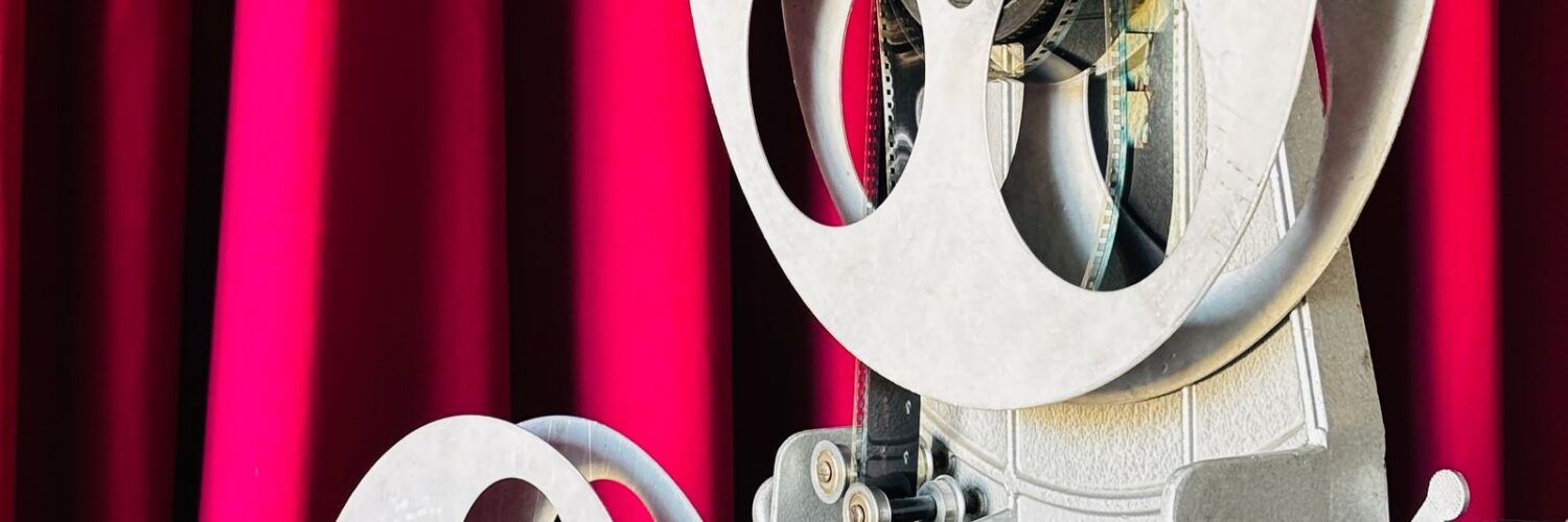 Vintage film projector in front of a red curtain