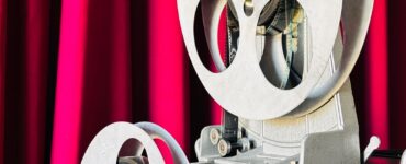 Vintage film projector in front of a red curtain