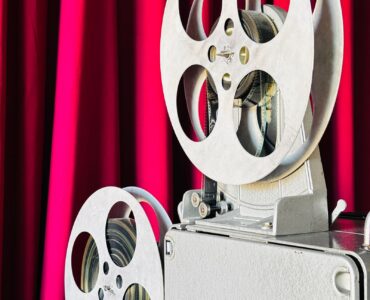 Vintage film projector in front of a red curtain