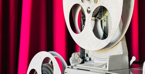 Vintage film projector in front of a red curtain