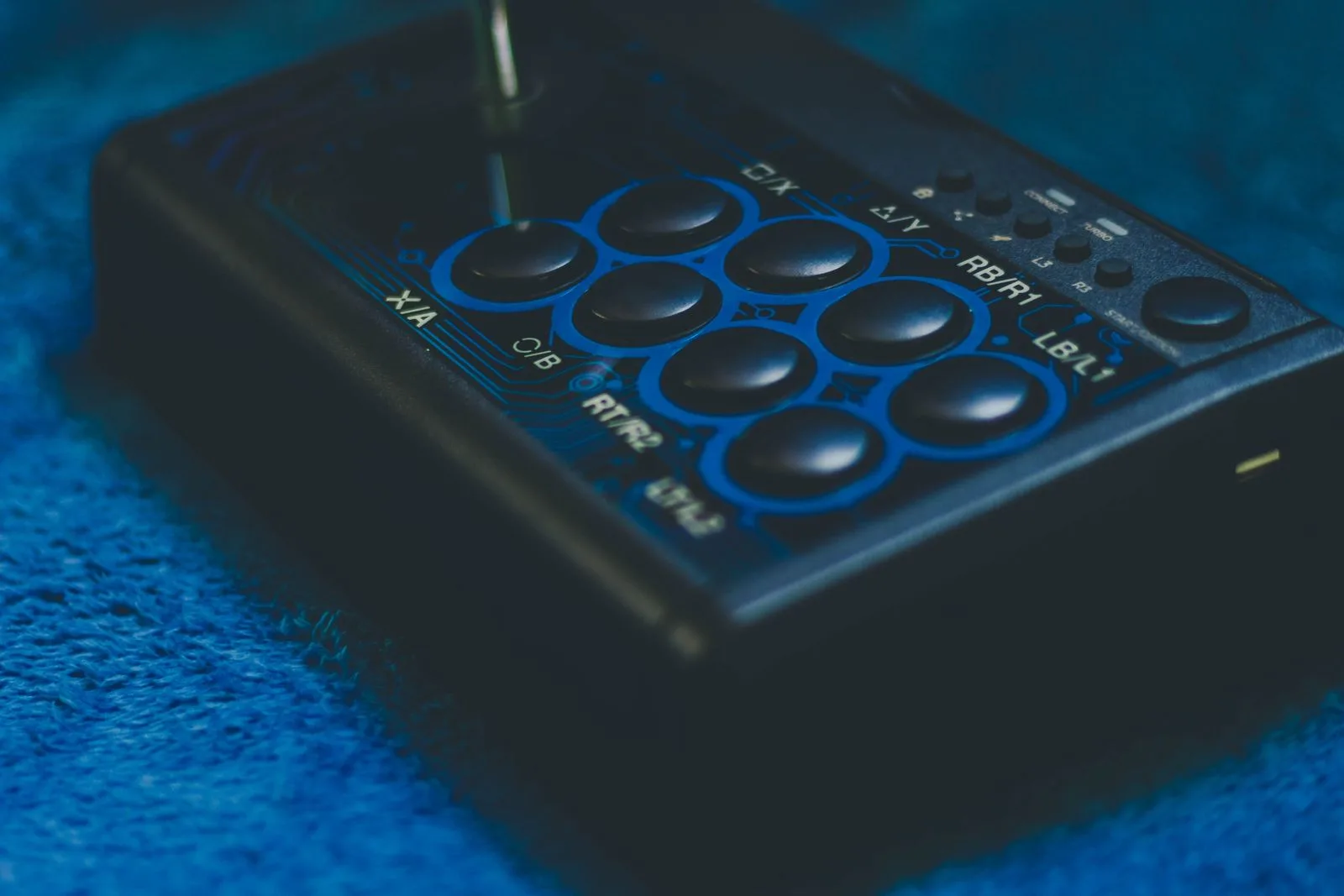 Game controller with buttons and joystick on a blue surface